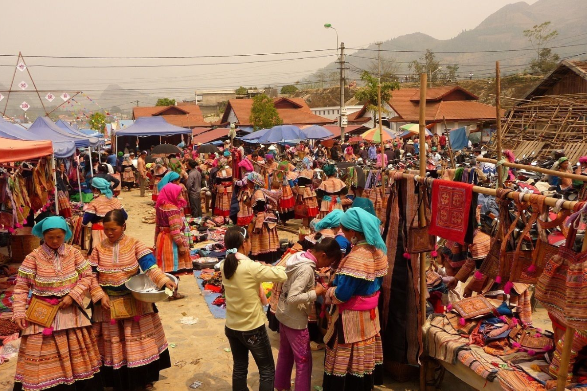 Market vendors and mountain tribespeople at Lung Khau Nhin surrounded by produce and textiles